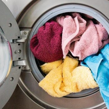 Red, pink, blue, and yellow towels in an open, front-loading washing machine